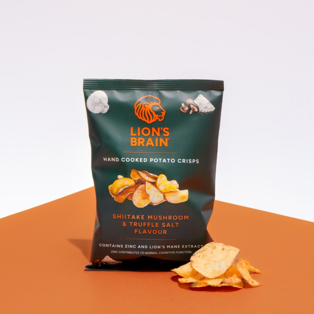 A bag of Lion's Brain hand cooked potato crisps in Shiitake Mushroom & Truffle Salt flavour, displayed on an orange surface against a white background with a few crisps placed in front.
